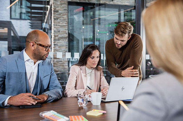 Vier Personen bei einem Meeting schauen auf einen Lap Top